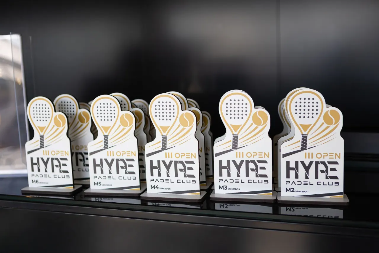 Troféus brancos e dourados em forma de raquete do III Open Hype Padel Club, de M2 a M6.